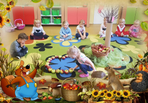 Dzieci siedzą na dywanie. Dziewczynka kładzie jabłko.